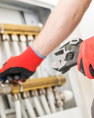 Hands fitting a brass central-heating manifold on a job in Islington