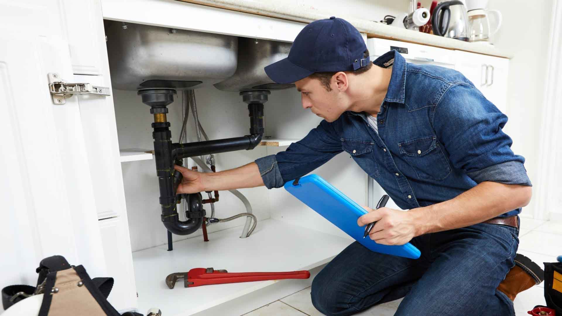 A Hartwell plumber at work under a kitchen sink in a North London home